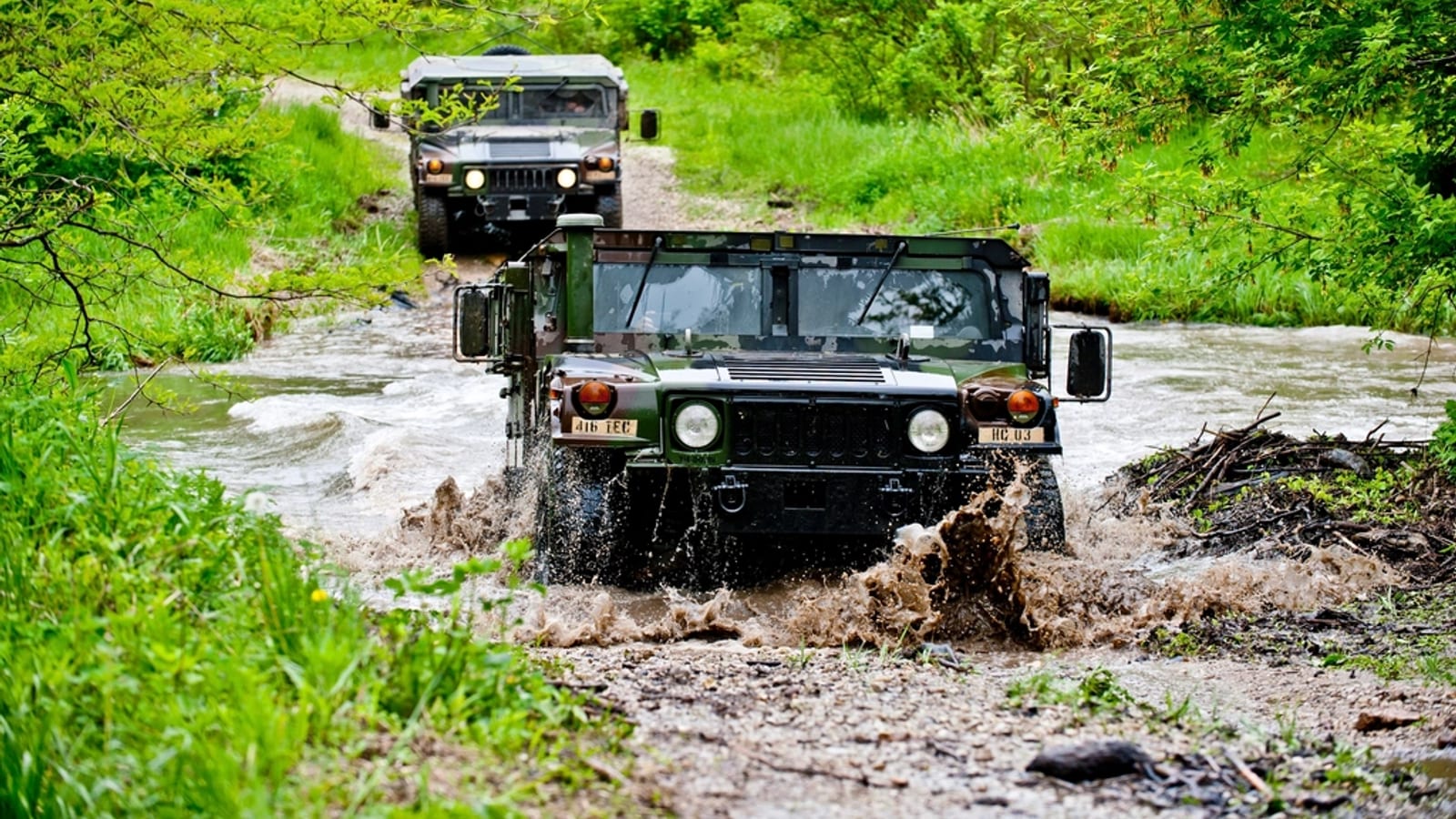 Two off road utility vehicles splashing through a shallow creek