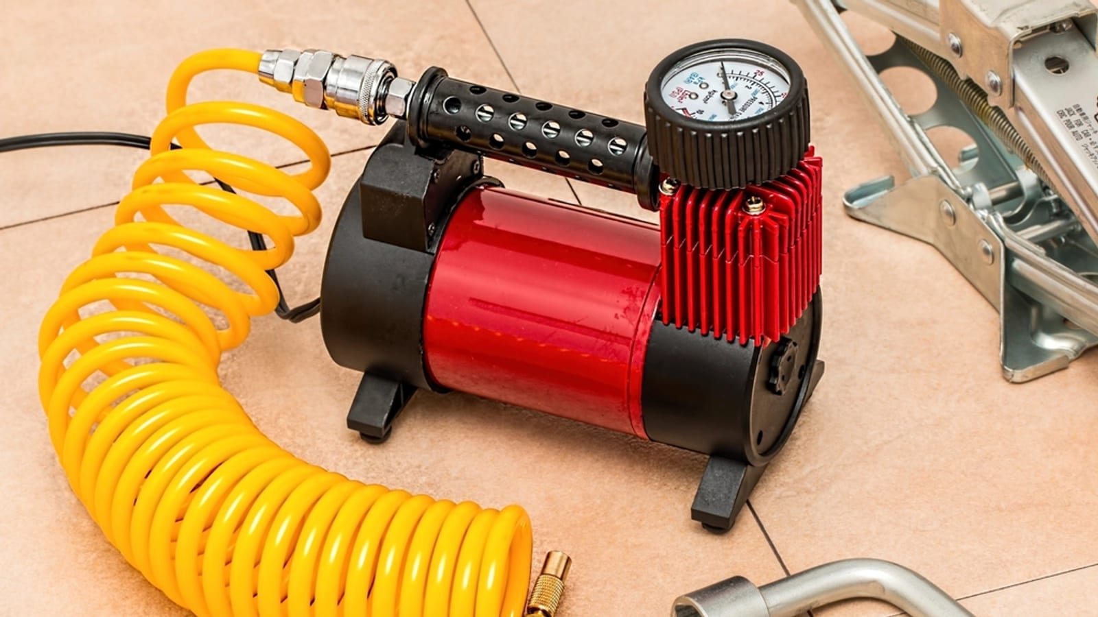 Why Tire Pressure Drops in Cold Weather and What to Do Simolary Portable air compressor with a pressure gauge and a coiled yellow hose