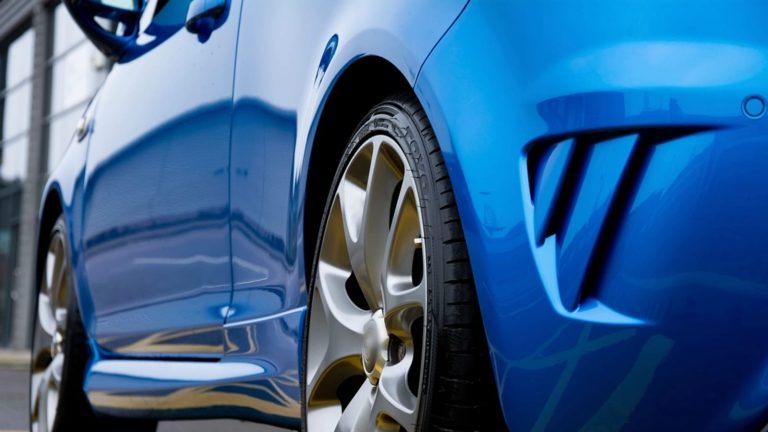 Close up of a blue cars front wheel and tire sidewall