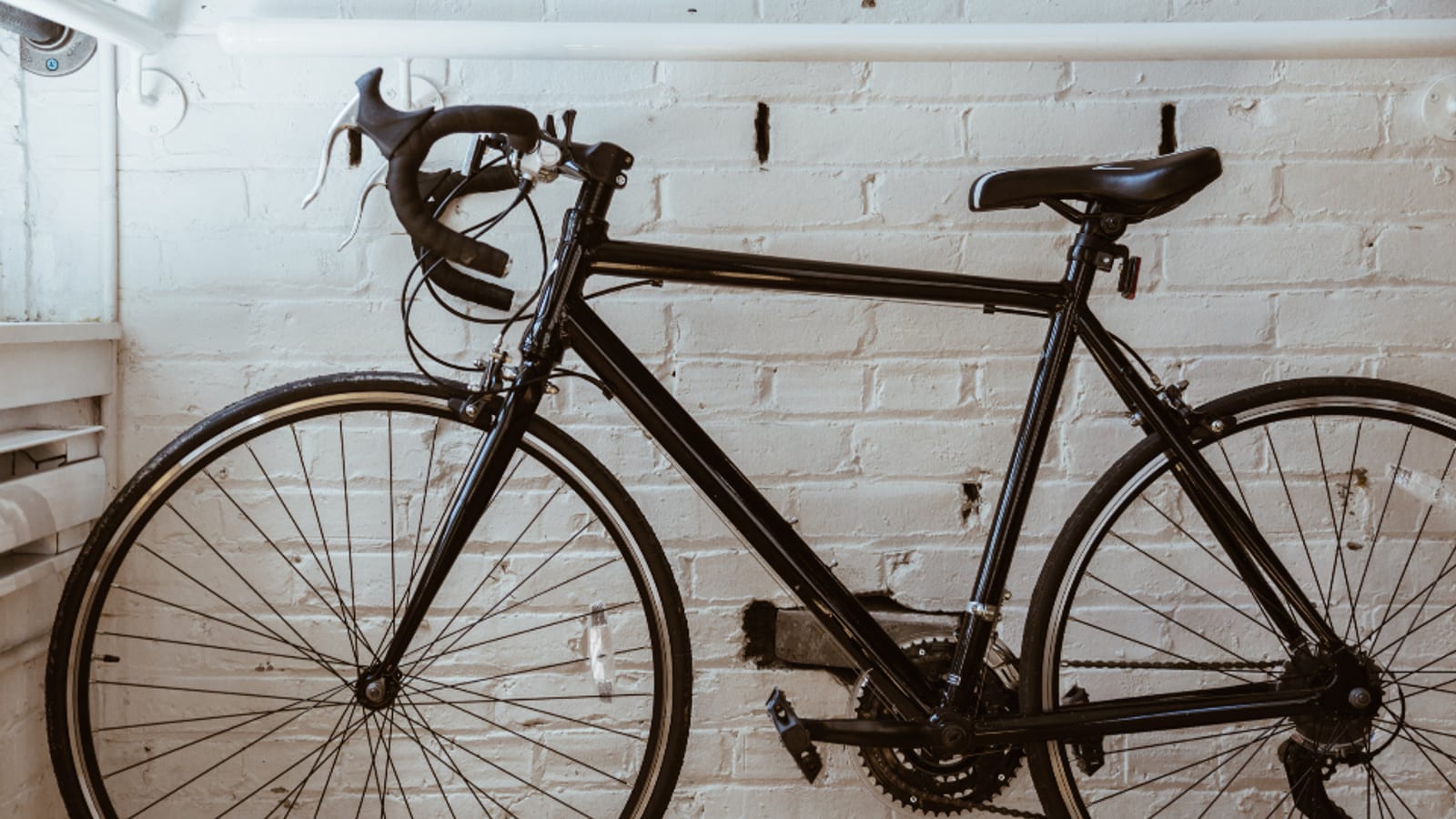 Indoor Bike Trainers Explained DirectDrive vs WheelOn Simolary Road bike leaning against a white brick wall