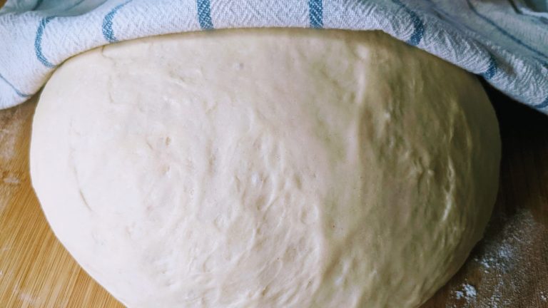 Ball of risen bread dough on a wooden board