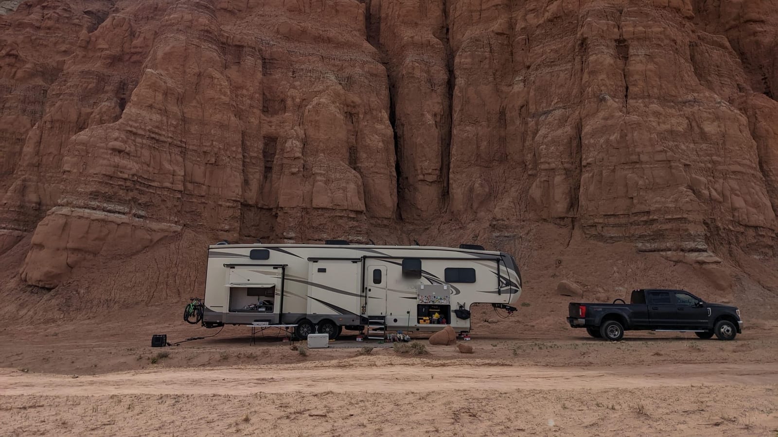 Fifth wheel camper and a heavy duty pickup parked below red rock cliffs